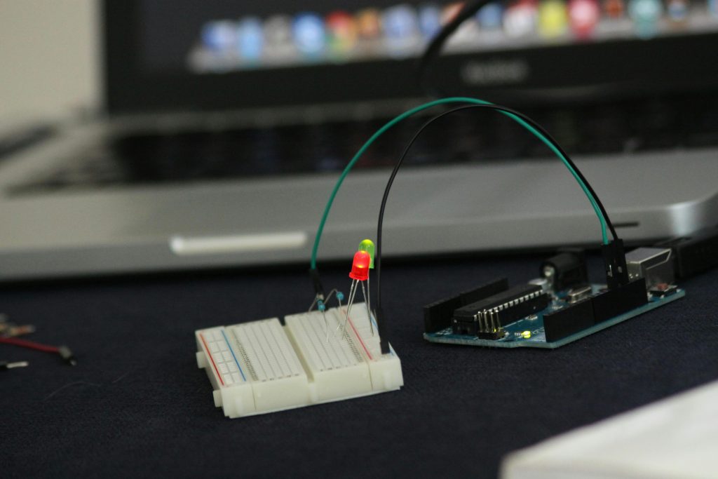 Close-up of an Arduino setup on a breadboard with glowing LED lights indoors.